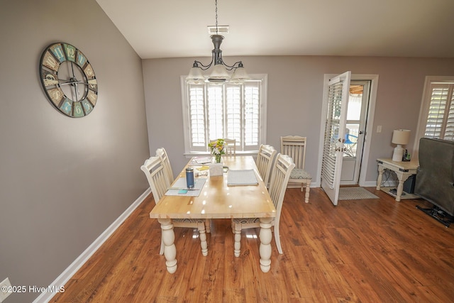 dining area with baseboards, a chandelier, and wood finished floors
