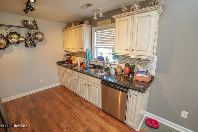 kitchen featuring backsplash, visible vents, stainless steel dishwasher, a sink, and baseboards