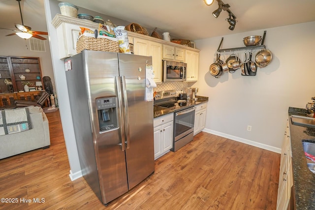 kitchen with a ceiling fan, appliances with stainless steel finishes, decorative backsplash, and light wood-style flooring