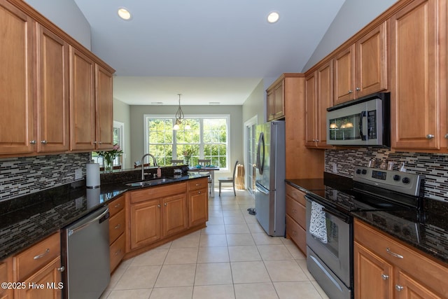 kitchen featuring brown cabinets, backsplash, appliances with stainless steel finishes, and a sink
