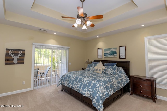 bedroom with a tray ceiling, visible vents, light carpet, and access to exterior
