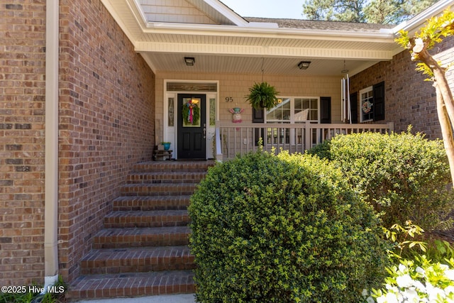 doorway to property featuring brick siding and covered porch