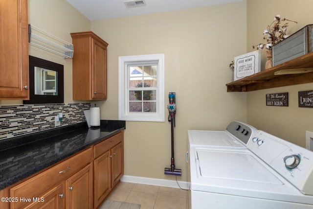laundry area featuring cabinet space, baseboards, light tile patterned floors, visible vents, and washer and clothes dryer