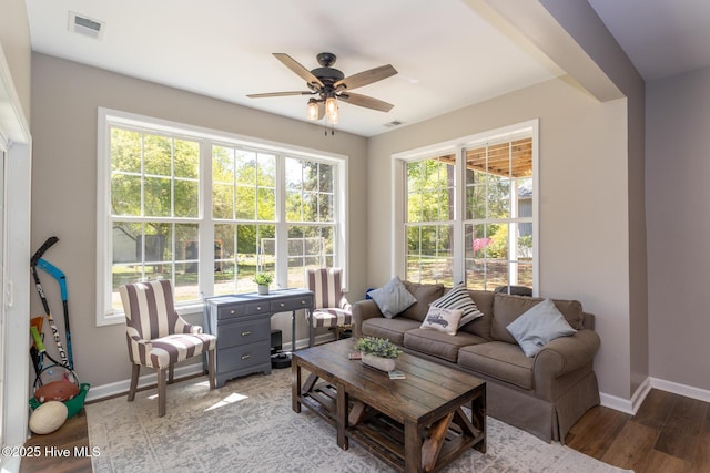 living room with baseboards, a ceiling fan, light wood finished floors, and visible vents