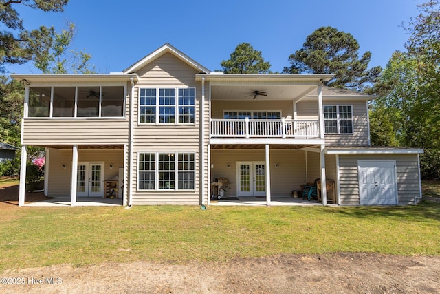rear view of property featuring ceiling fan, french doors, a deck, a yard, and a patio