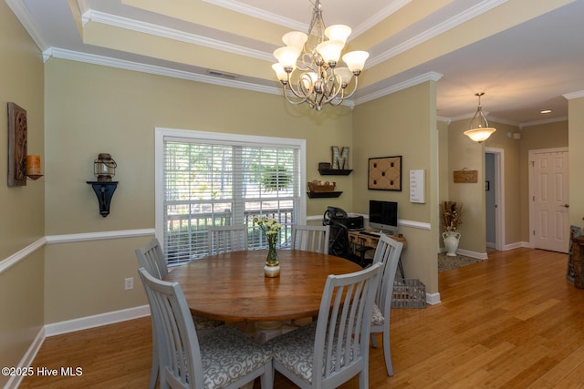dining area featuring visible vents, crown molding, a notable chandelier, and light wood-type flooring