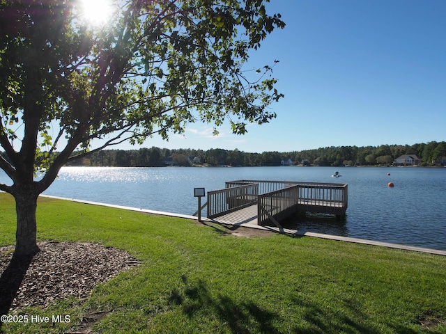 dock area featuring a water view, a yard, and a wooded view