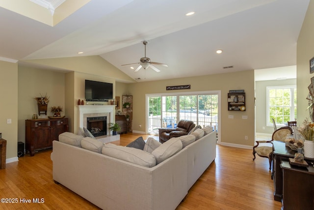 living area with a tile fireplace, a healthy amount of sunlight, and light wood-type flooring