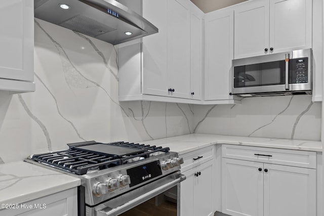 44 S Shamrock Dr, Foxfire Village, NC 27281 - kitchen with appliances with stainless steel finishes, ventilation hood, white cabinetry, tasteful backsplash, and light stone counters