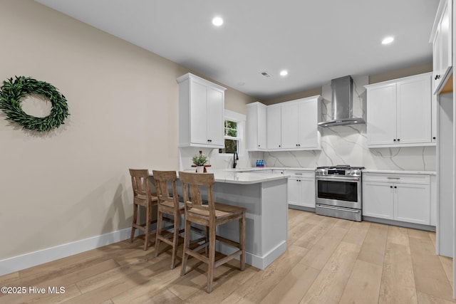 44 S Shamrock Dr, Foxfire Village, NC 27281 - kitchen featuring wall chimney exhaust hood, stainless steel gas range oven, a peninsula, light countertops, and light wood-style flooring