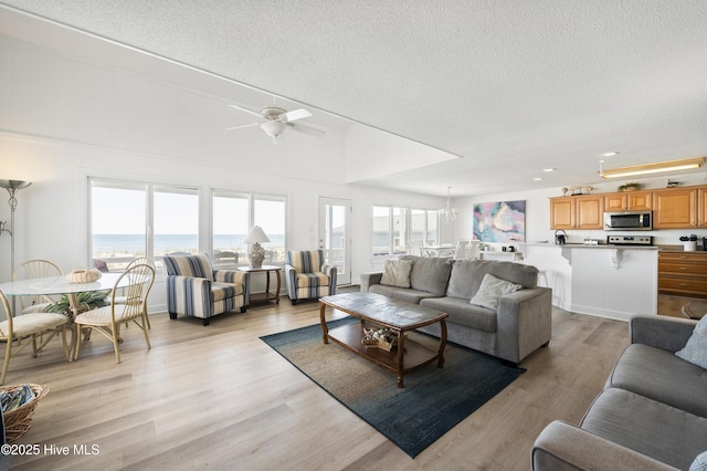 living room featuring ceiling fan, a fireplace, wood finished floors, and a towering ceiling