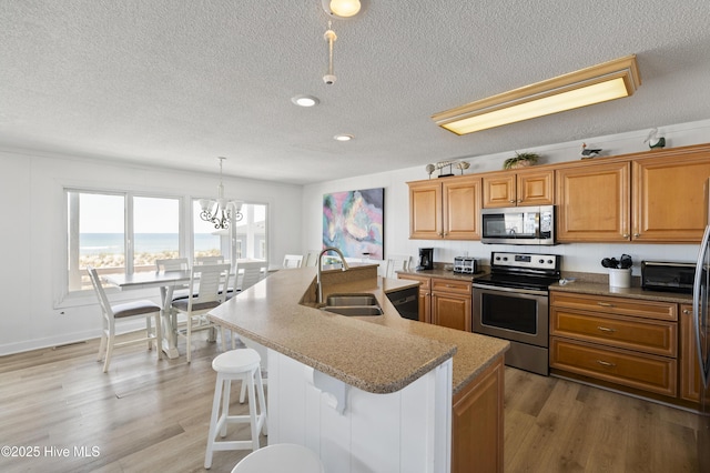 kitchen featuring open floor plan, a textured ceiling, brown cabinets, a sink, and dishwasher