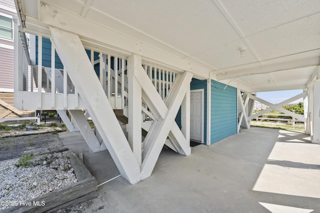 rear view of house with stairs, a carport, and driveway