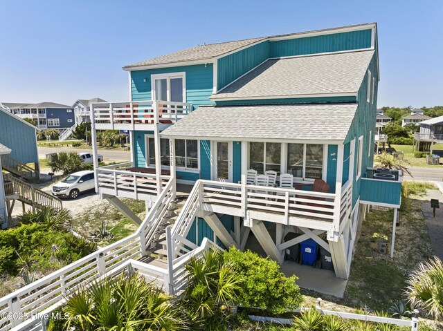 rear view of house with stairway, a balcony, and roof with shingles