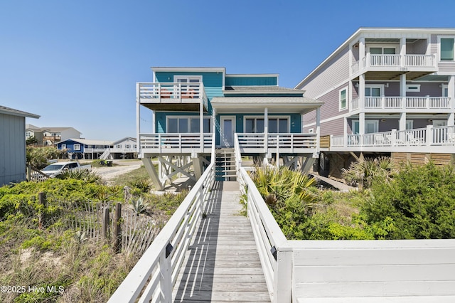 back of house with roof with shingles, stairs, a balcony, and a residential view