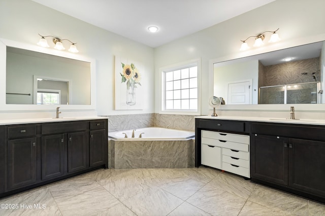 bathroom with a garden tub, a shower stall, two vanities, a sink, and marble finish floor