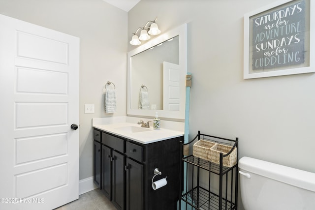 half bathroom with vanity, baseboards, tile patterned flooring, and toilet