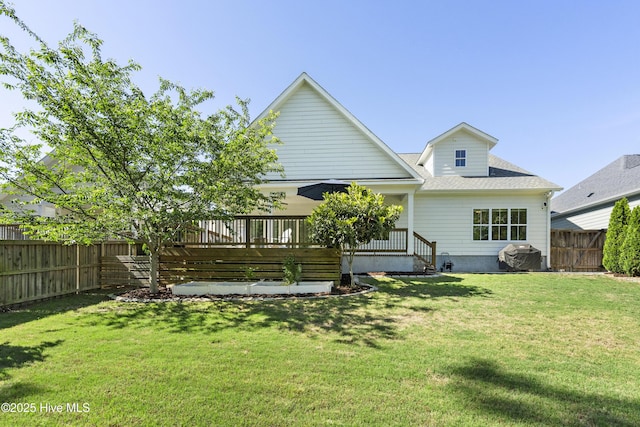 rear view of house featuring a fenced backyard, a shingled roof, and a lawn