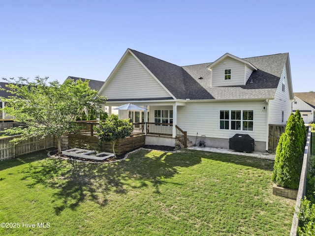 rear view of house with a fenced backyard, a shingled roof, a yard, and a deck