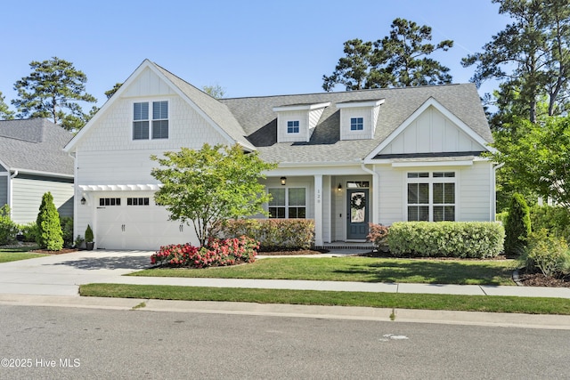 view of front of property with board and batten siding, driveway, a front yard, an attached garage, and a shingled roof