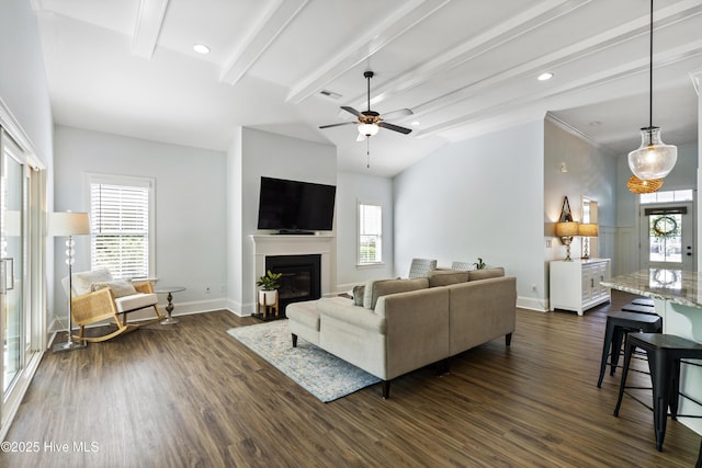 living room featuring a ceiling fan, dark wood finished floors, beam ceiling, baseboards, and a glass covered fireplace