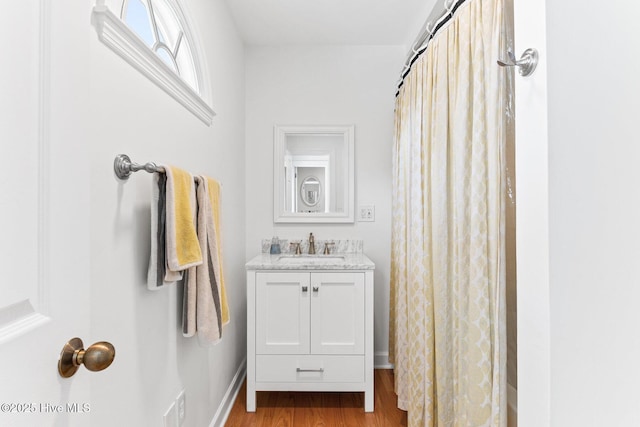 bathroom with baseboards, wood finished floors, and vanity
