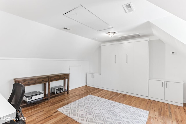 additional living space with attic access, lofted ceiling, wood finished floors, and visible vents