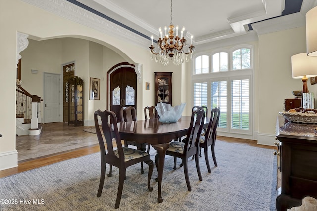 2220 Bel Arbor Pl, Wilmington, NC 28403 - dining area featuring stairs, a chandelier, ornamental molding, wood finished floors, and arched walkways