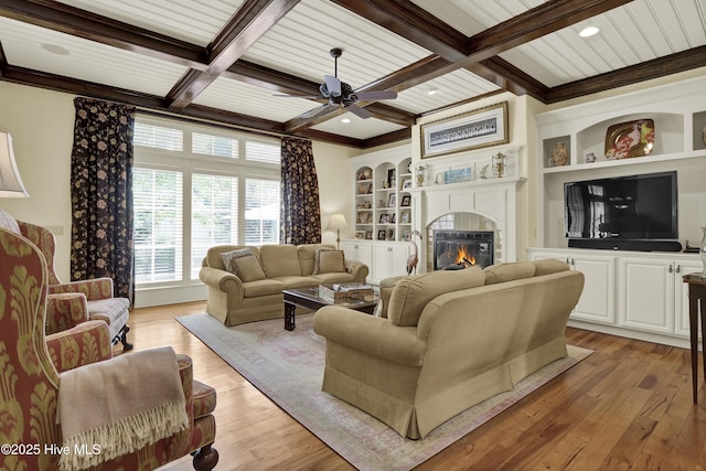 2220 Bel Arbor Pl, Wilmington, NC 28403 - living area featuring beamed ceiling, a glass covered fireplace, light wood-style flooring, a ceiling fan, and coffered ceiling