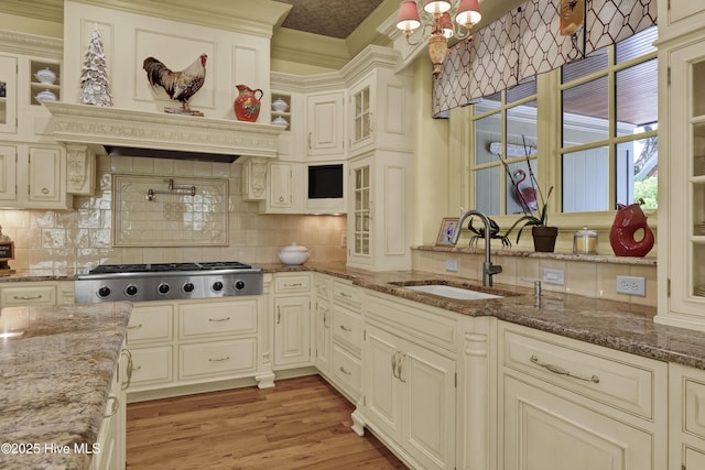 2220 Bel Arbor Pl, Wilmington, NC 28403 - kitchen featuring stainless steel gas stovetop, decorative backsplash, glass insert cabinets, light wood-style floors, and crown molding