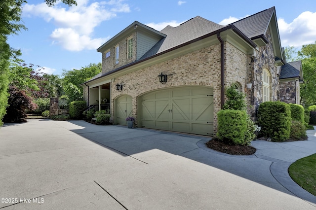 2220 Bel Arbor Pl, Wilmington, NC 28403 - view of home's exterior with driveway, stone siding, a shingled roof, and a garage