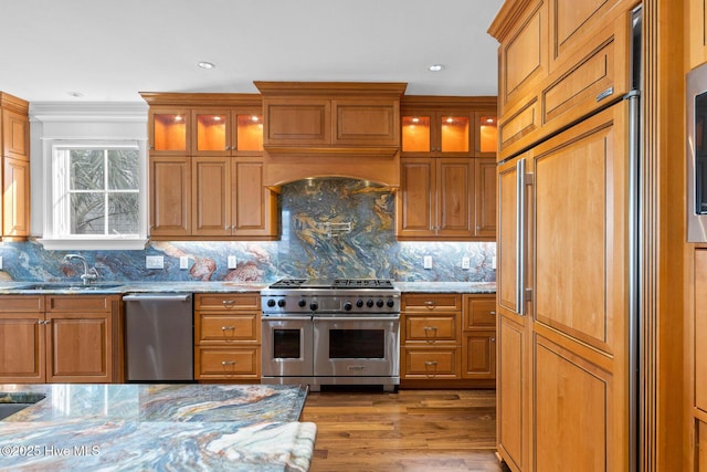 805 S Lumina Ave, Wrightsville Beach, NC 28480 - kitchen with light stone countertops, glass insert cabinets, brown cabinetry, a sink, and high end appliances