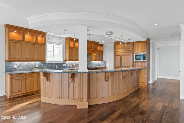 805 S Lumina Ave, Wrightsville Beach, NC 28480 - kitchen featuring a breakfast bar area, glass insert cabinets, stainless steel microwave, and dark wood-style floors