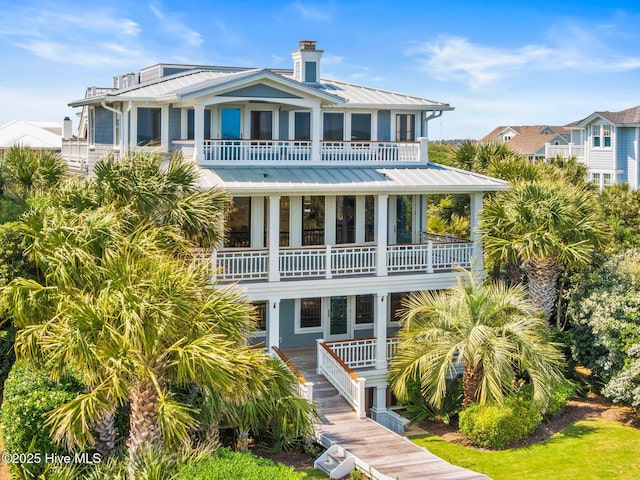 805 S Lumina Ave, Wrightsville Beach, NC 28480 - rear view of house featuring a balcony, metal roof, a standing seam roof, and a chimney