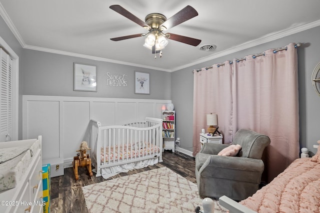 415 W Boardwalk Blvd, Atlantic Beach, NC 28512 - bedroom featuring crown molding, dark wood-style floors, a nursery area, ceiling fan, and a decorative wall