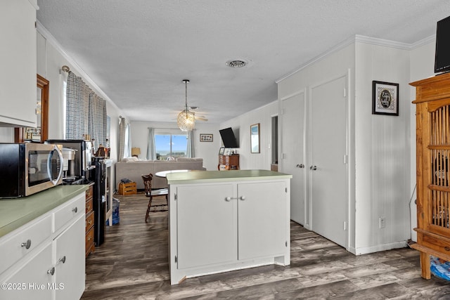 415 W Boardwalk Blvd, Atlantic Beach, NC 28512 - kitchen featuring stainless steel microwave, ceiling fan, dark wood-style flooring, a kitchen island, and white cabinets