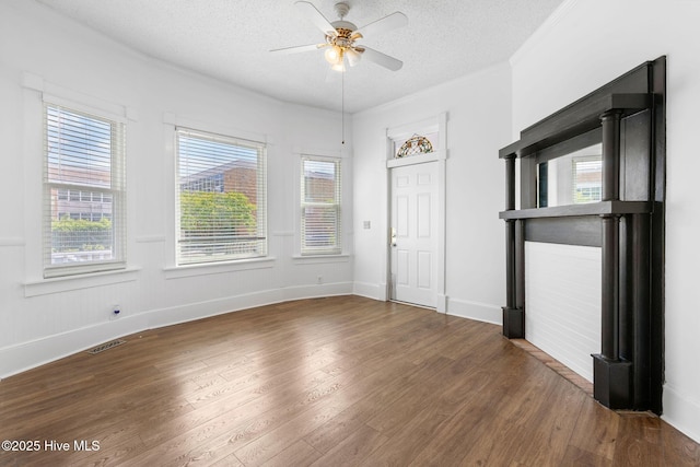 interior space with a ceiling fan, a textured ceiling, visible vents, and wood finished floors