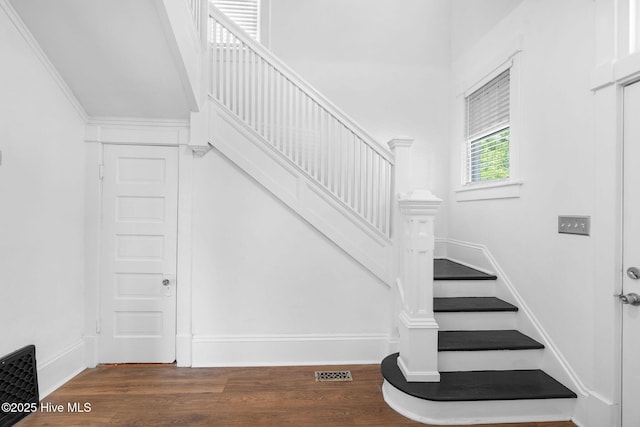 staircase with visible vents, baseboards, and wood finished floors