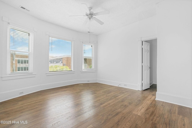 spare room featuring visible vents, baseboards, ceiling fan, and wood finished floors