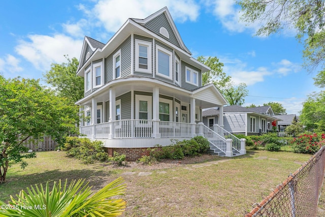 victorian-style house with a porch, a front lawn, and fence
