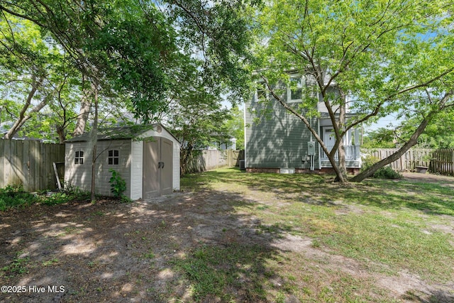 view of yard with a fenced backyard, an outbuilding, and a shed