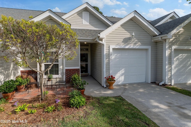 multi unit property with roof with shingles, an attached garage, and driveway