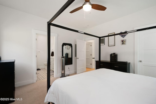 bedroom with baseboards, light colored carpet, and ensuite bathroom