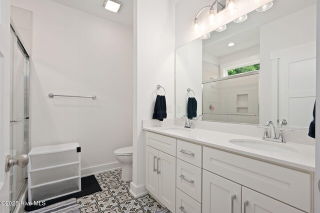 full bath featuring double vanity, toilet, tiled shower, and a sink