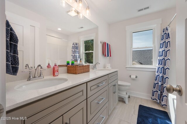 bathroom featuring a sink, toilet, and visible vents