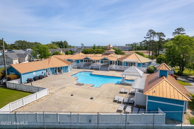 community pool with a fenced backyard, a patio area, and a residential view