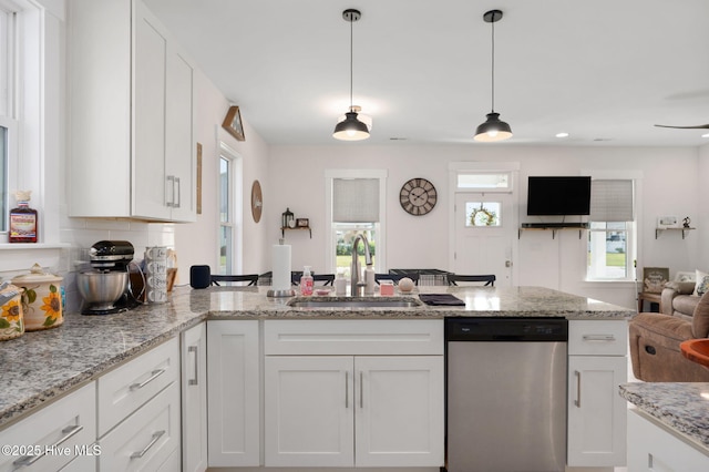 kitchen featuring open floor plan, a sink, dishwasher, and white cabinets