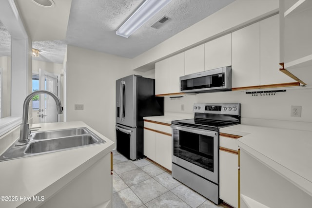 kitchen with a textured ceiling, visible vents, appliances with stainless steel finishes, a sink, and light countertops