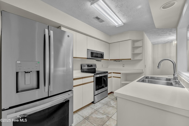 kitchen featuring open shelves, light countertops, a textured ceiling, a sink, and appliances with stainless steel finishes