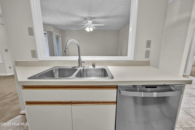 kitchen featuring stainless steel dishwasher, a sink, a ceiling fan, and light countertops
